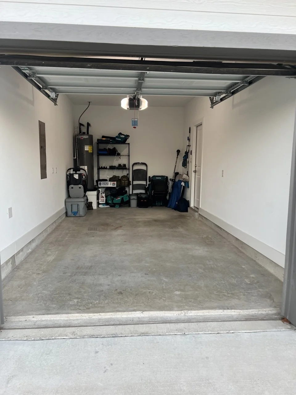 Clean single-car garage with tools and bins organized at the back