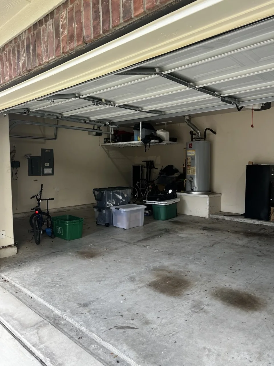 Garage side view showing storage bins, bike, and water heater area